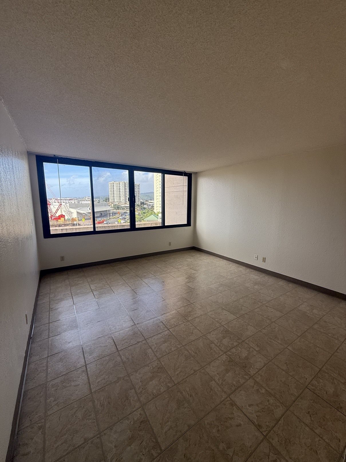 A room with a large window and tiled flooring.